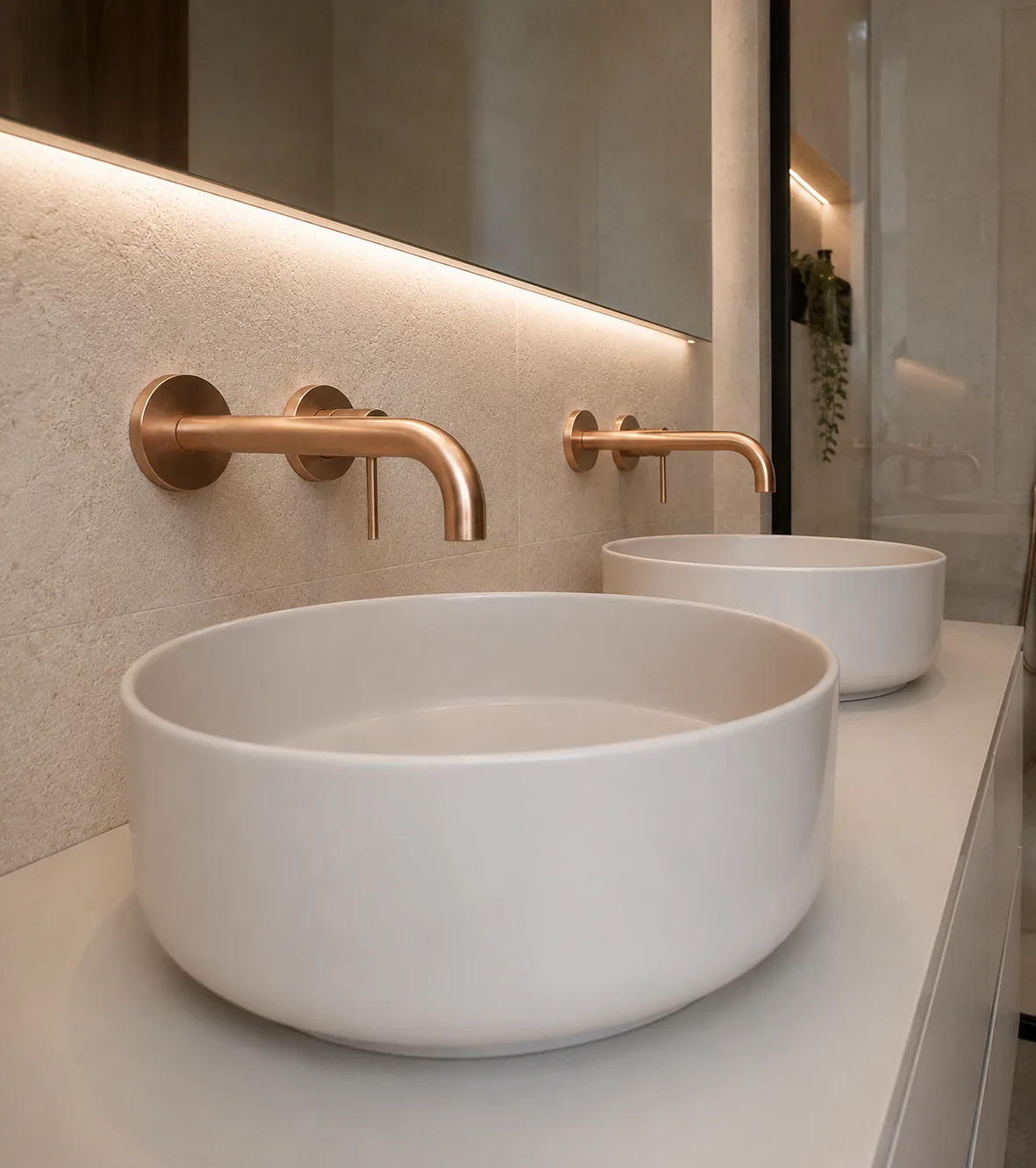 Detalle de doble lavabo sobrepuesto en cerámica blanca con grifería empotrada en tono cobre.