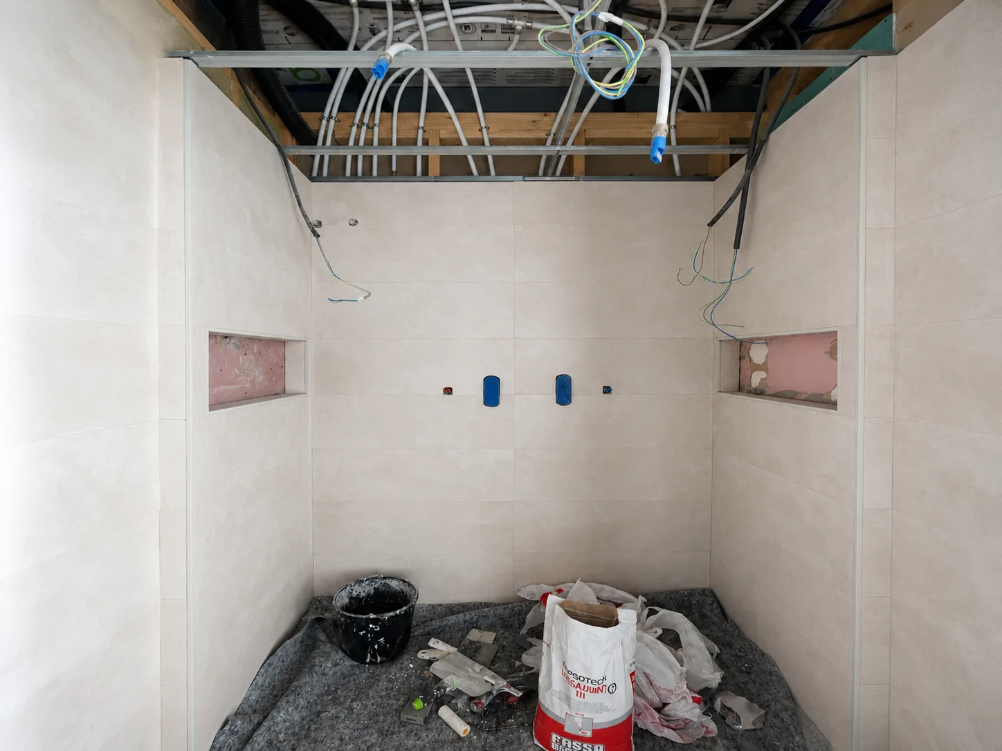 Baño en fase de obra con instalación eléctrica y de fontanería vista antes del alicatado final.